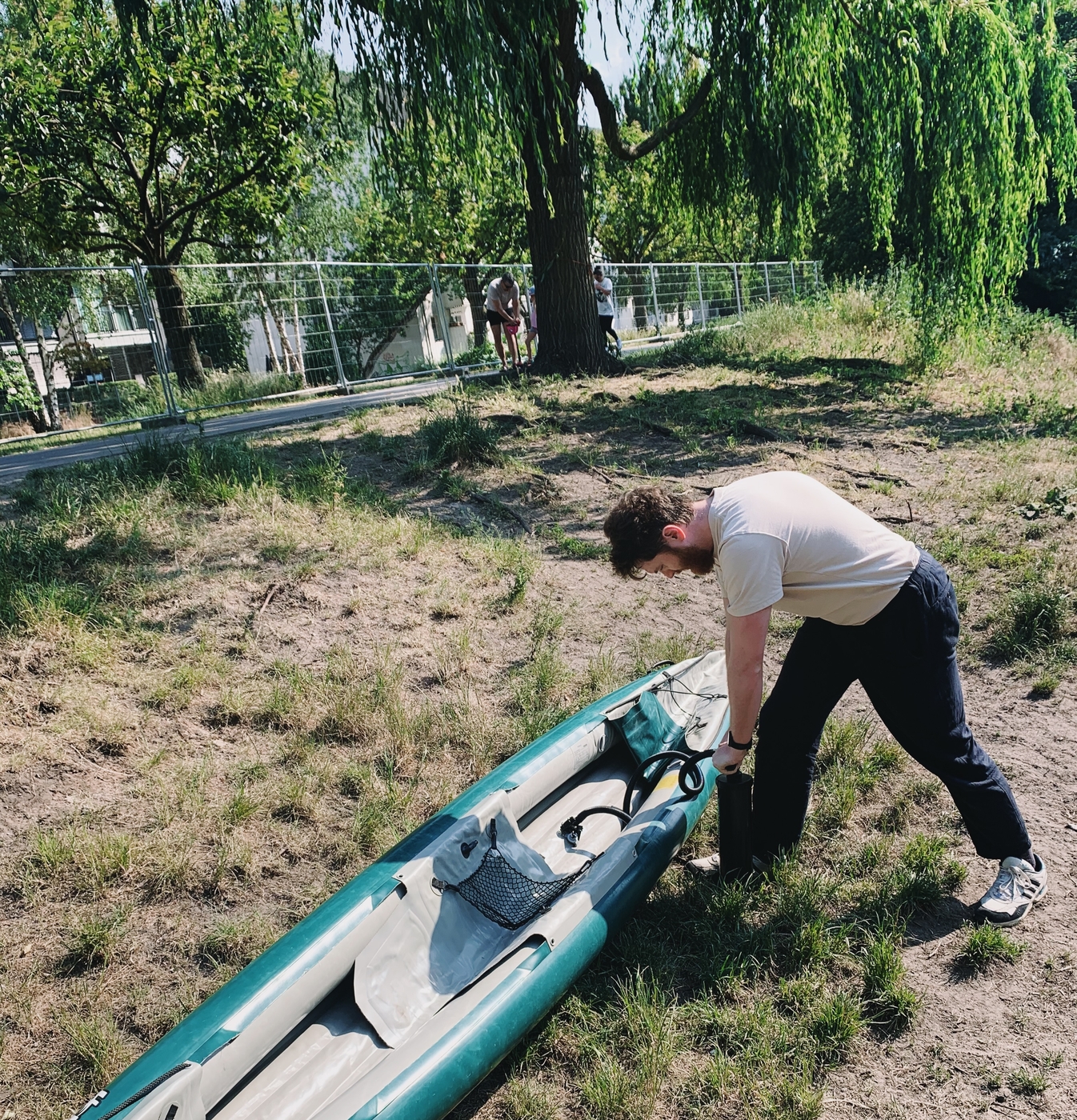 Jack pumping up an inflatable kayak on a grassy bank