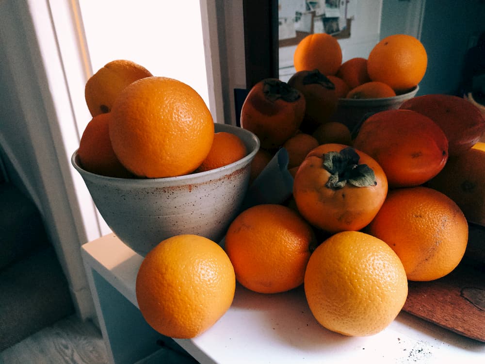 Oranges in a bowl in front of a mirror