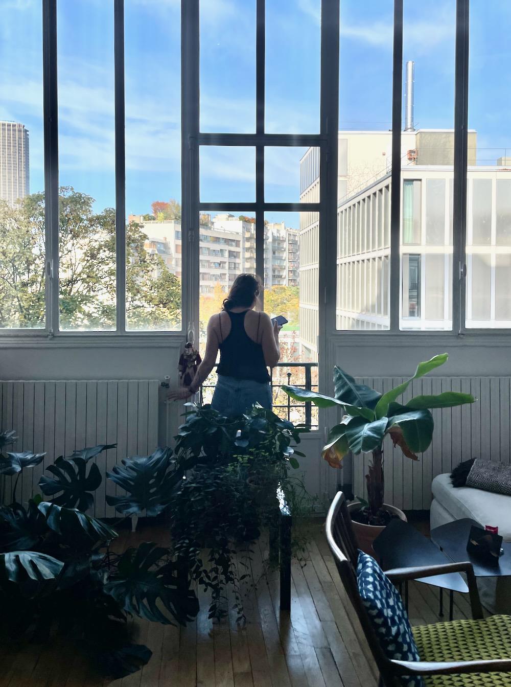 A girl in front of the windows of a bright apartment