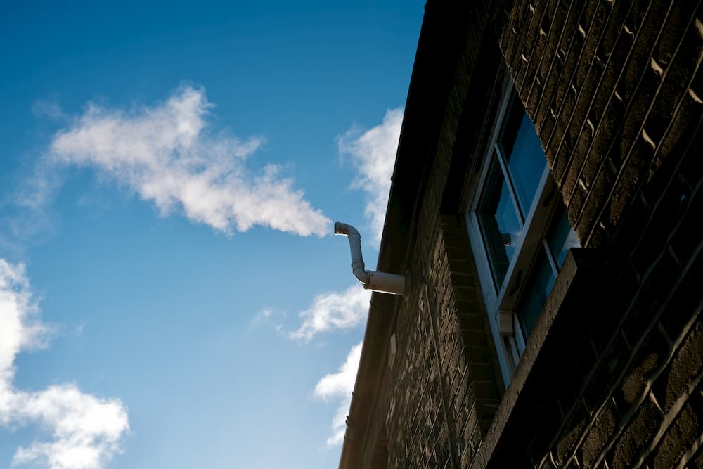 Steam coming out of a pipe against a blue sky of clouds that look similar