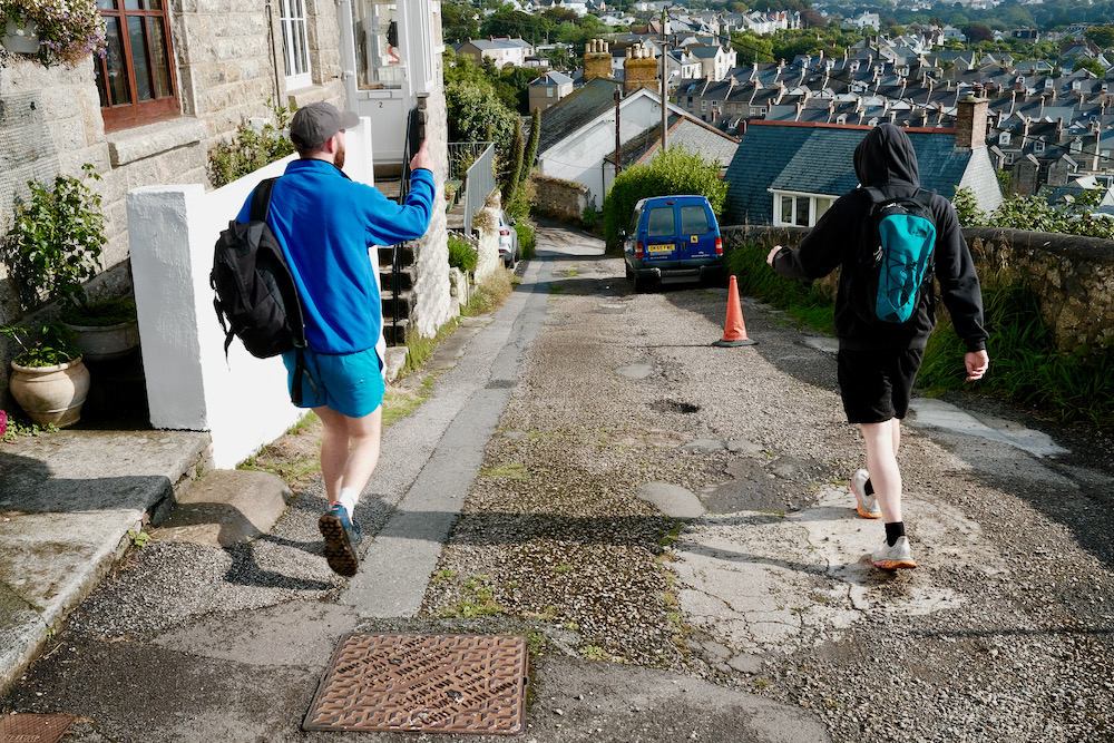 Two men walking down a road to the sea