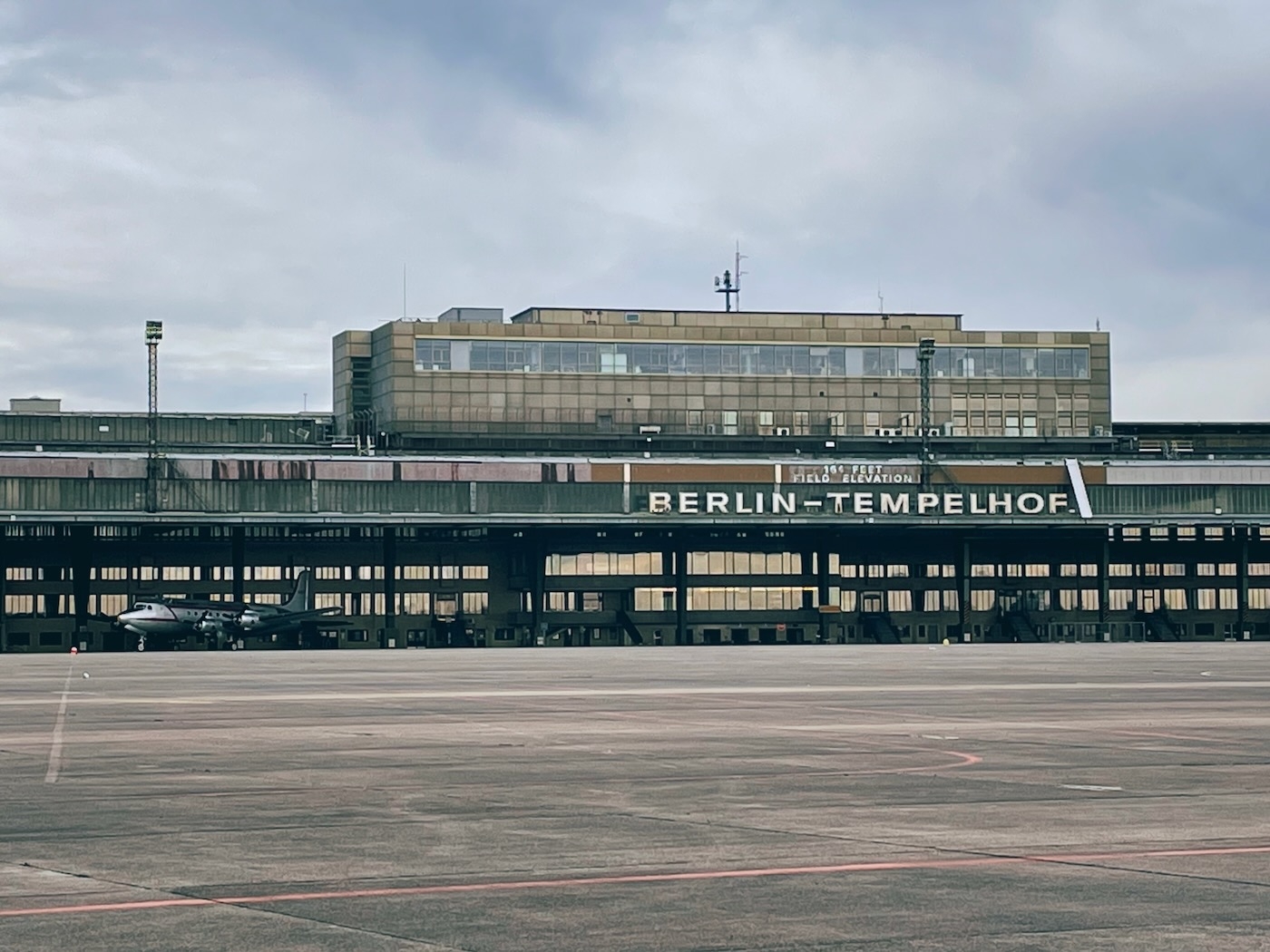 The terminal building of the old Tempelhof Airport with a 50s style plane parked at the front