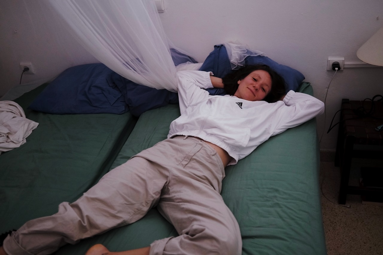 A girl lying on a bed in slacks and a hoodie