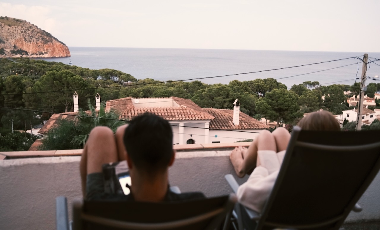 Two people reading books on a balcony above the bay