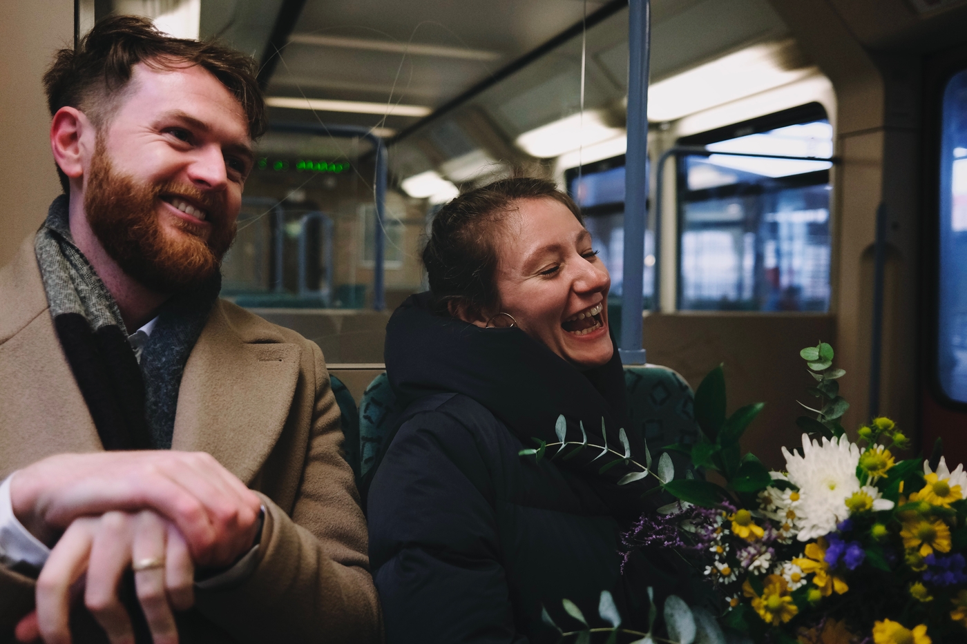 A bride and groom laughing while sitting on a train