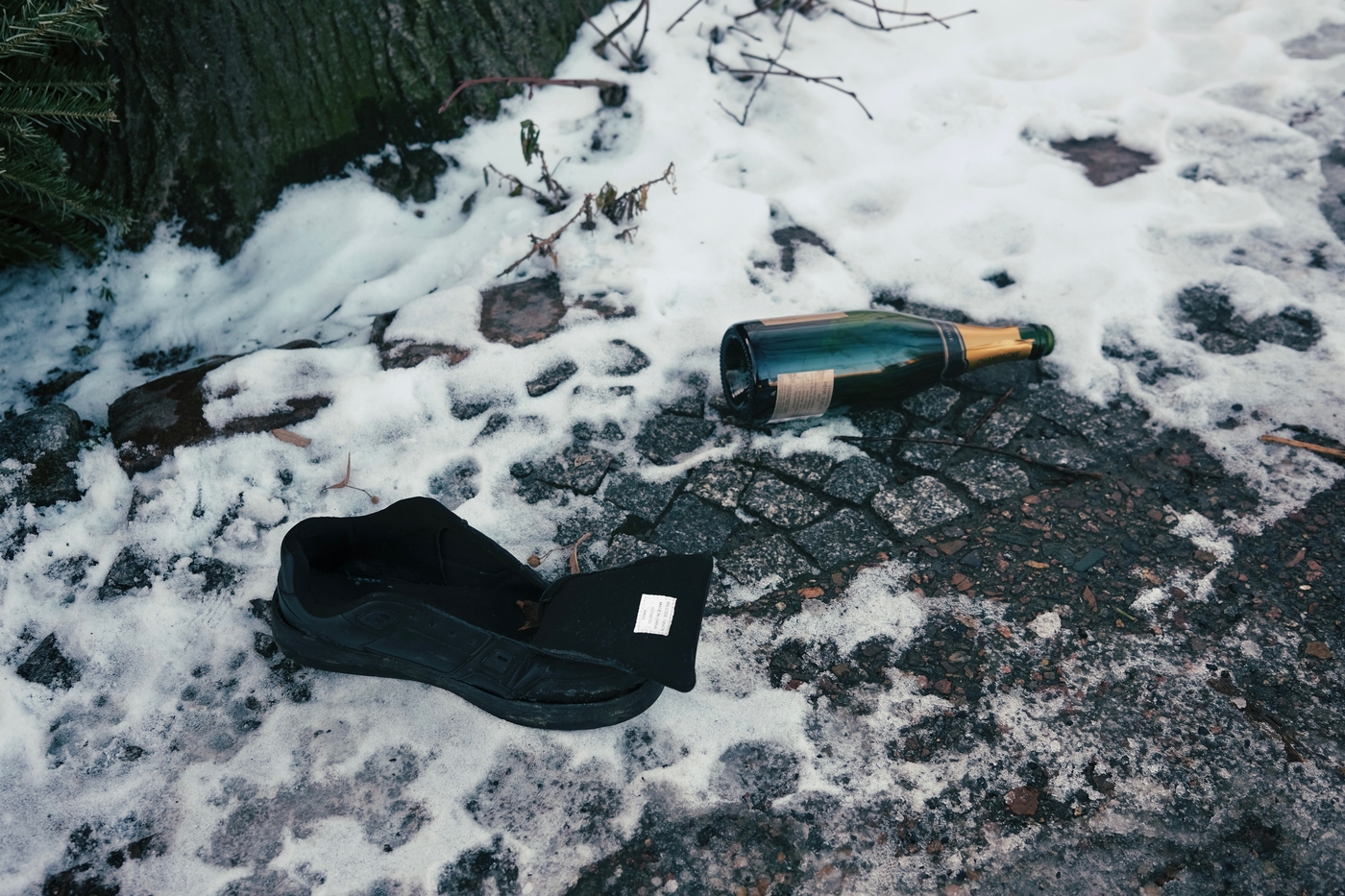 A discarded shoe and bottle of sekt on a snowy pavement in Berlin