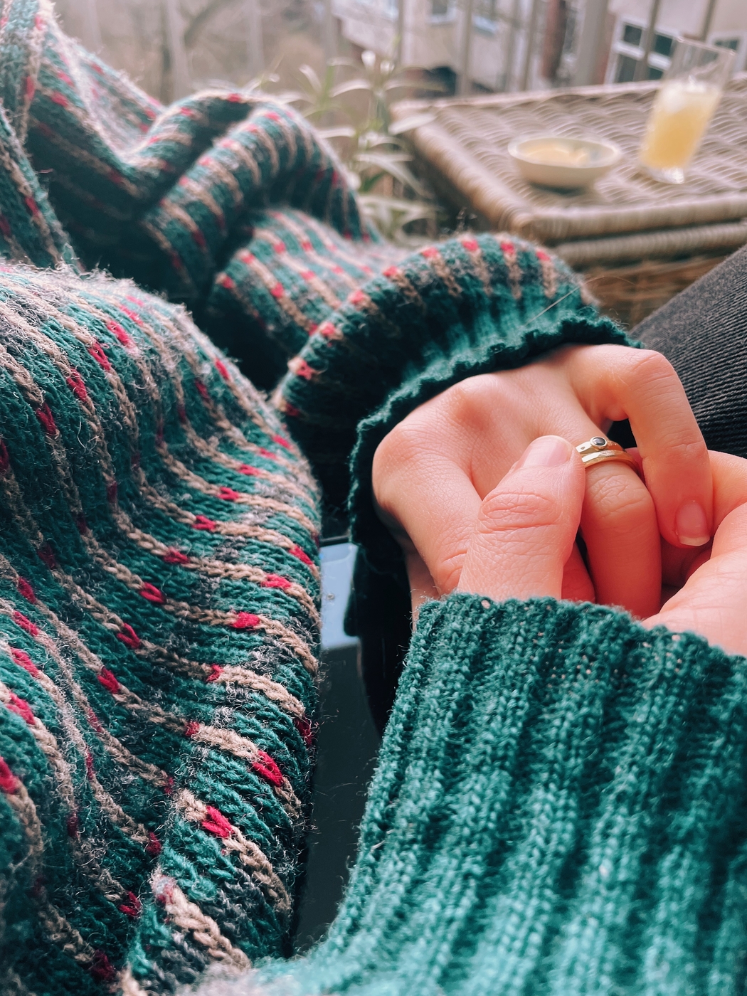 A close up a scratchy jumper and hands wearing rings